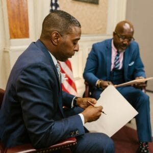 two men in blue suit holding a folder