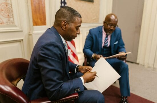 two men in blue suit holding a folder