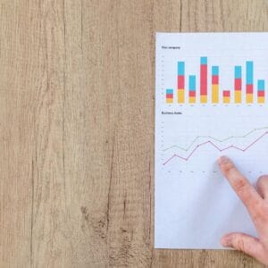 person pointing paper line graph